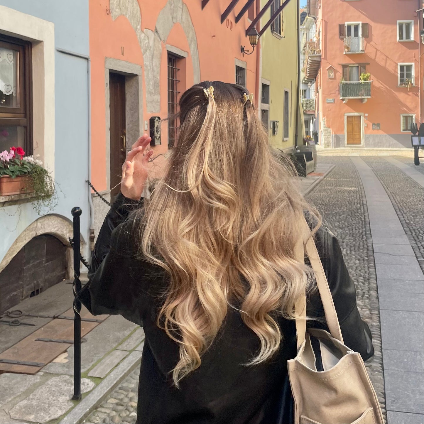 Eine junge Frau von hinten mit langen Haaren, die ein Set aus zwei herzförmigen Haarspangen in beige in ihren Haaren trägt. Der Look ähnelt einem Festival Look und wurde in Domodossola aufgenommen.
