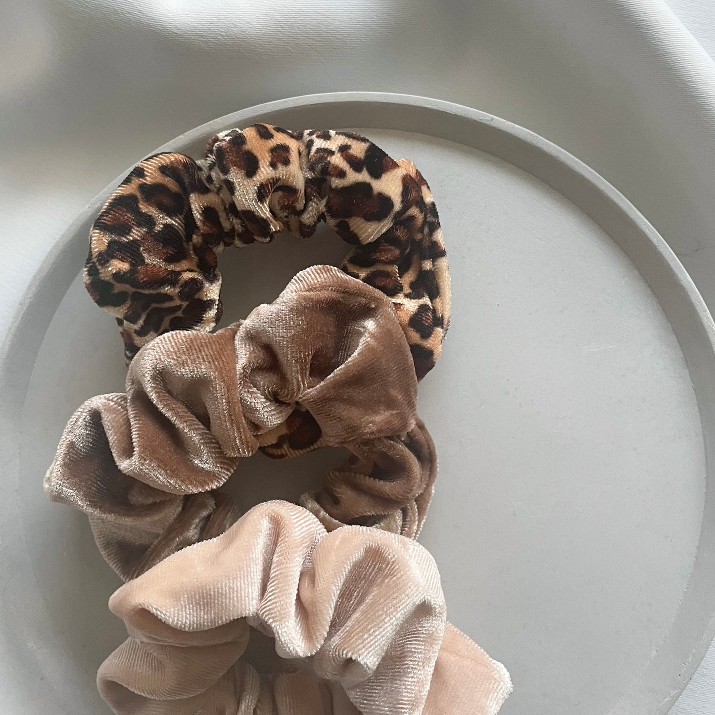 drei Scrunchies die in einer grauen Schmuckschale liegen