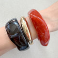 Drei Armreifen in gold, rot & dunkelbraun, die Bangles werden getragen präsentiert.
