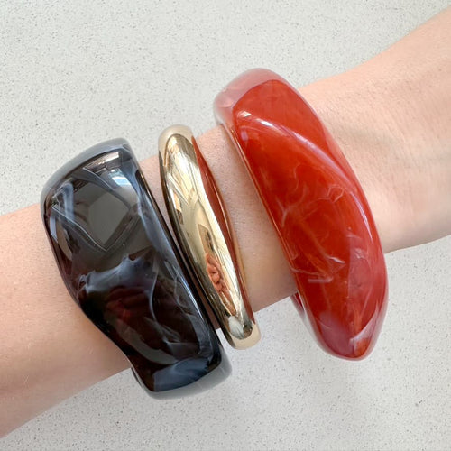 Drei Armreifen in gold, rot & dunkelbraun, die Bangles werden getragen präsentiert.