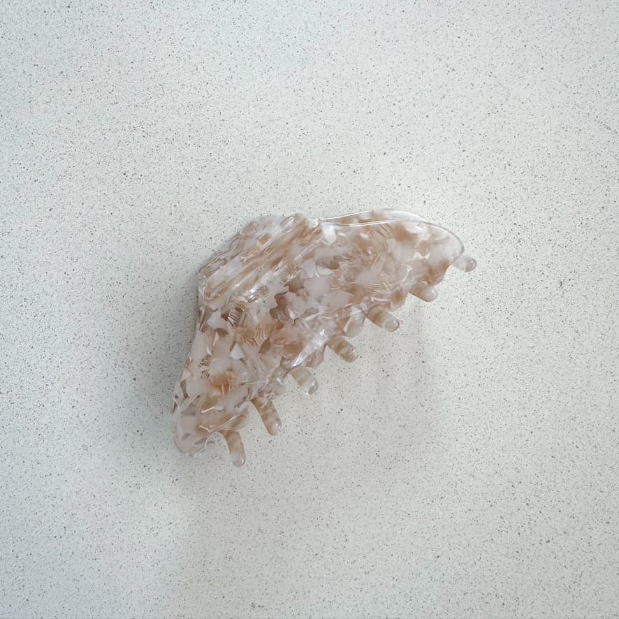Auf dem Bild ist eine grosse Haarklammer in beige zu sehen, die Haarklammer wird als Produktfoto auf einem neutralen Hintergrund präsentiert.