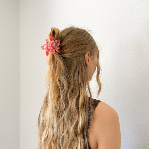 Auf dem Bild ist eine blumenförmige Haarklammer in pink zu sehen, die Haarklammer wird getragen präsentiert.