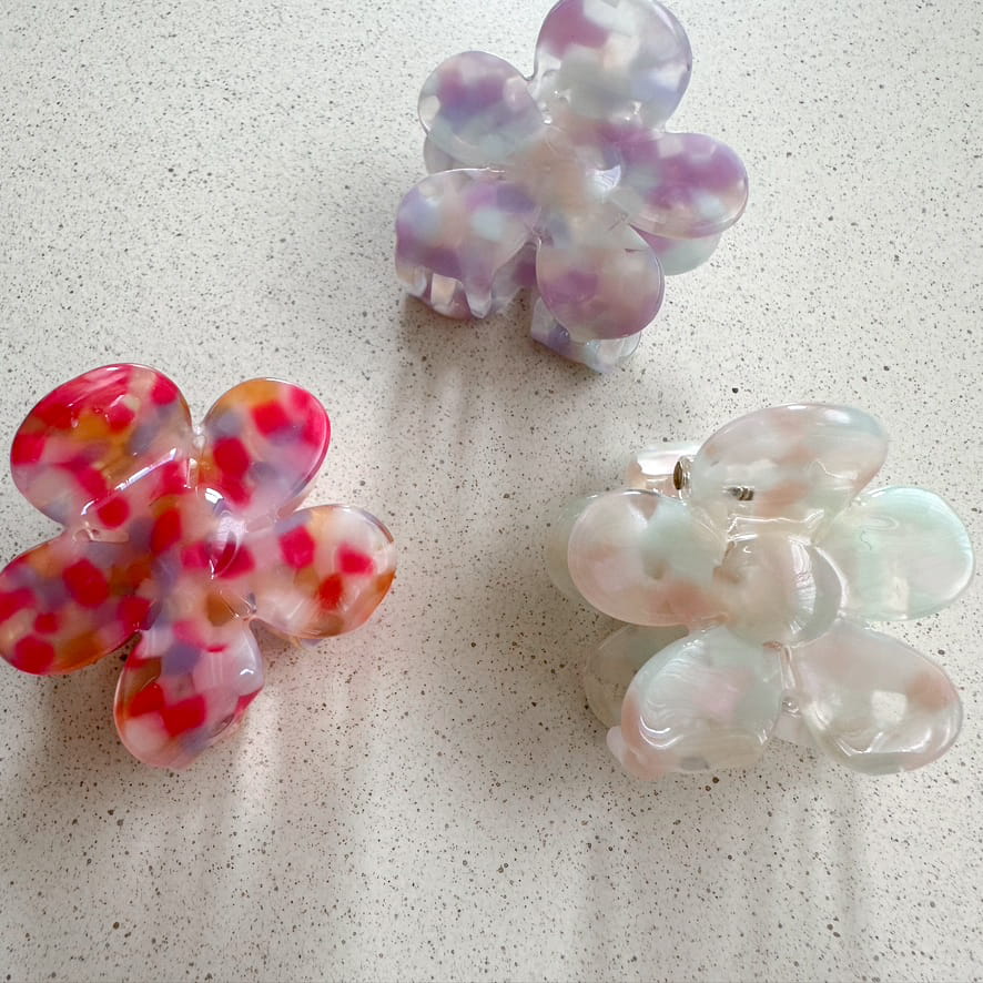 Auf dem Bild sind drei kleine blumenförmige Haarklammer in hellen Pastellfarben zu sehen, die Haarklammern werden als Produktfoto auf einem neutralen Hintergrund präsentiert.