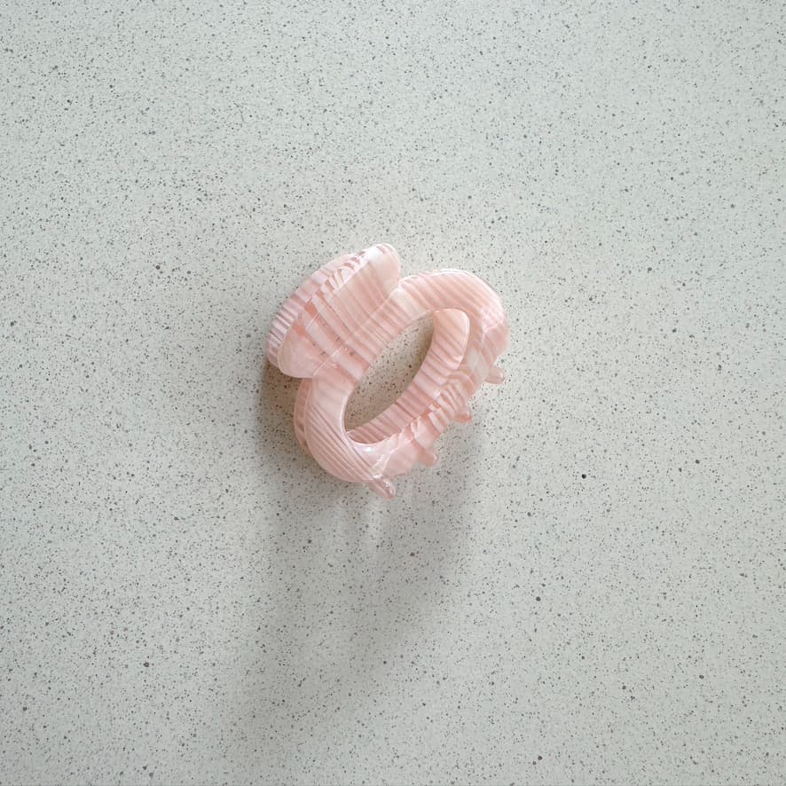 Auf dem Bild ist eine kleine runde Haarklammer in rosa zu sehen, die Haarklammer wird als Produktfoto auf einem neutralen Hintergrund präsentiert.