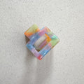 Auf dem Bild ist eine kleine quadratische Haarklammer in knalligen Farben zu sehen, die Haarklammer wird als Produktfoto auf einem neutralen Hintergrund präsentiert.
