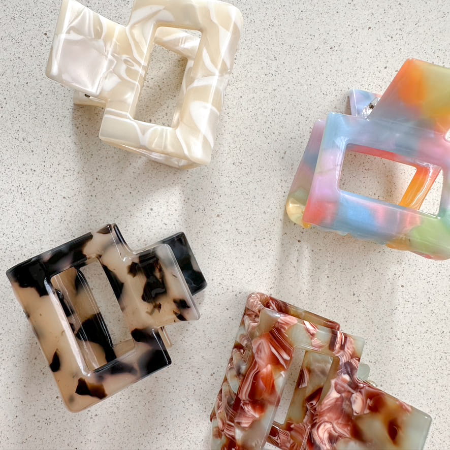 Auf dem Bild sind vier kleine quadratische Haarklammer in beige, bunt, türkis & tortoise zu sehen, die Haarklammern werden als Produktfoto auf einem neutralen Hintergrund präsentiert.