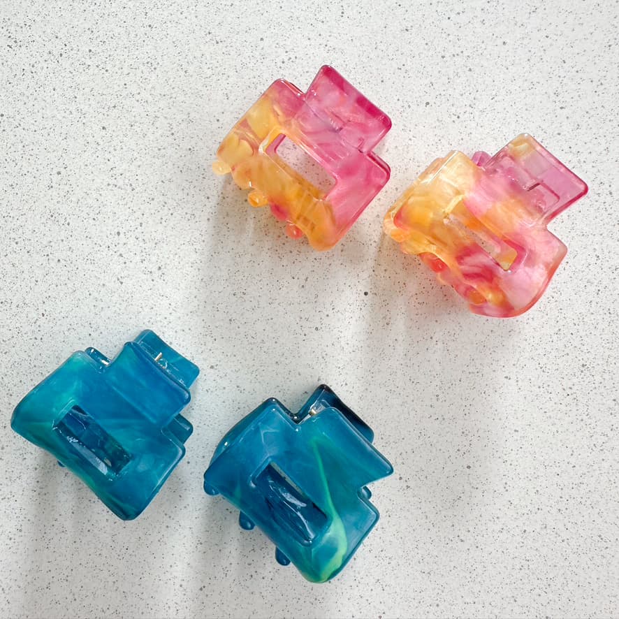 Auf dem Bild sind vier kleine mini Haarklammer in verschiedenen Farben zu sehen, die Haarklammen werden als Produktfoto auf einem neutralen Hintergrund präsentiert.
