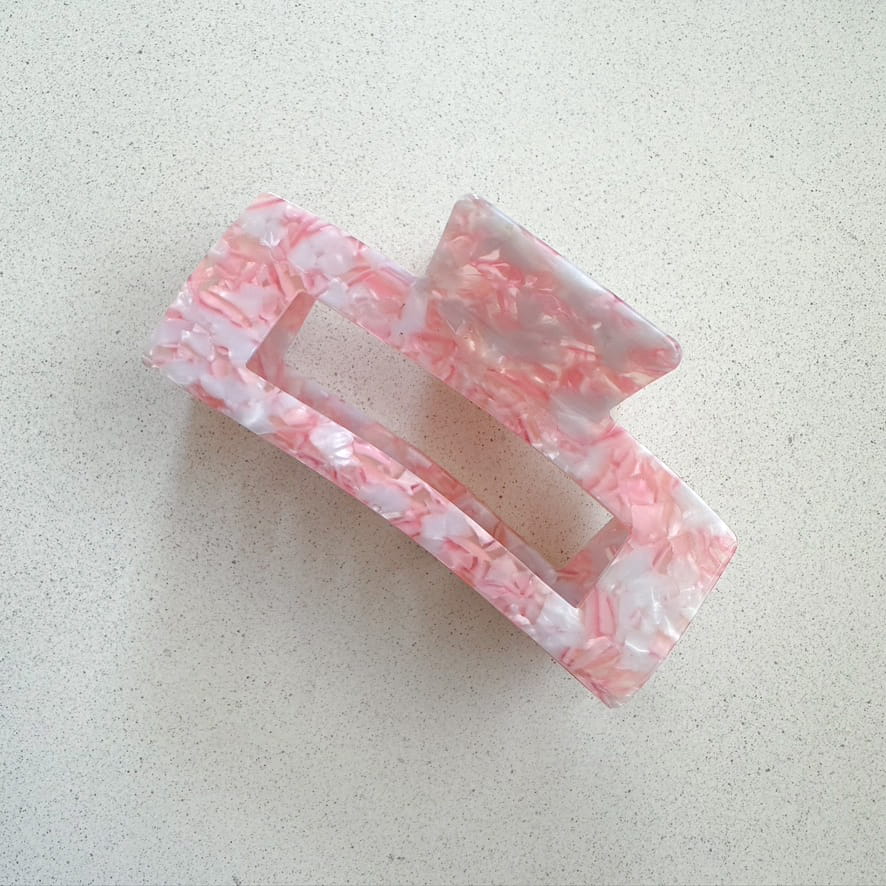 Auf dem Bild ist eine grosse Haarklammer in rosa zu sehen, die Haarklammer wird als Produktfoto auf einem neutralen Hintergrund präsentiert.