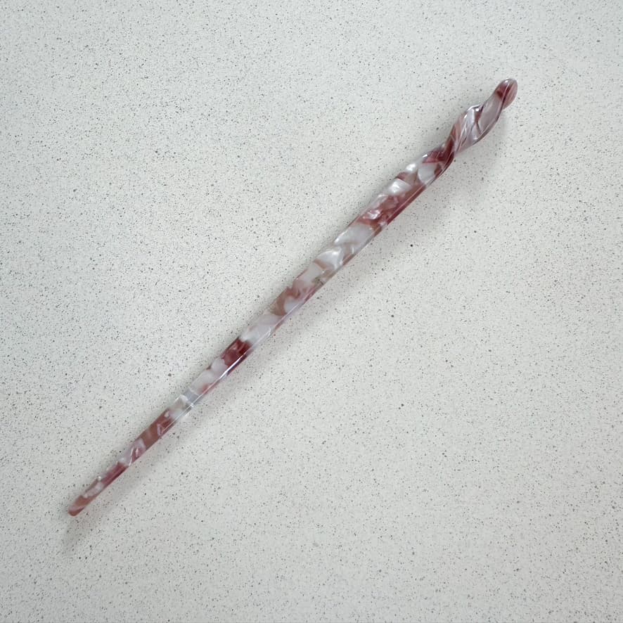 Auf dem Bild ist ein Haarstab in rosa zu sehen, der Haarstab wird als Produktfoto auf einem neutralen Hintergrund präsentiert.