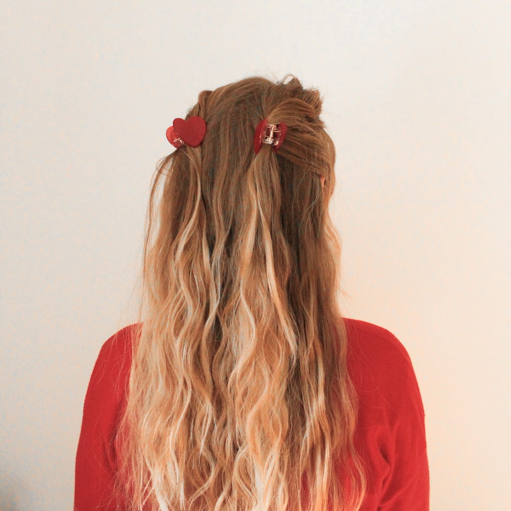 zwei kleine rote Herzhaarklammern getragen in langem blondem Haar