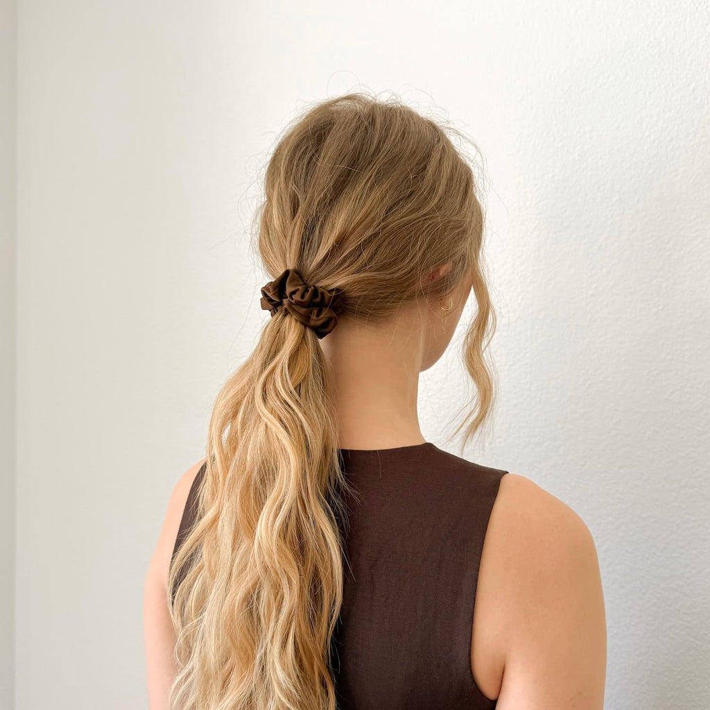 Auf dem Bild sind ist ein braunes Scrunchie zu sehen, das Scrunchies wird getragen präsentiert.