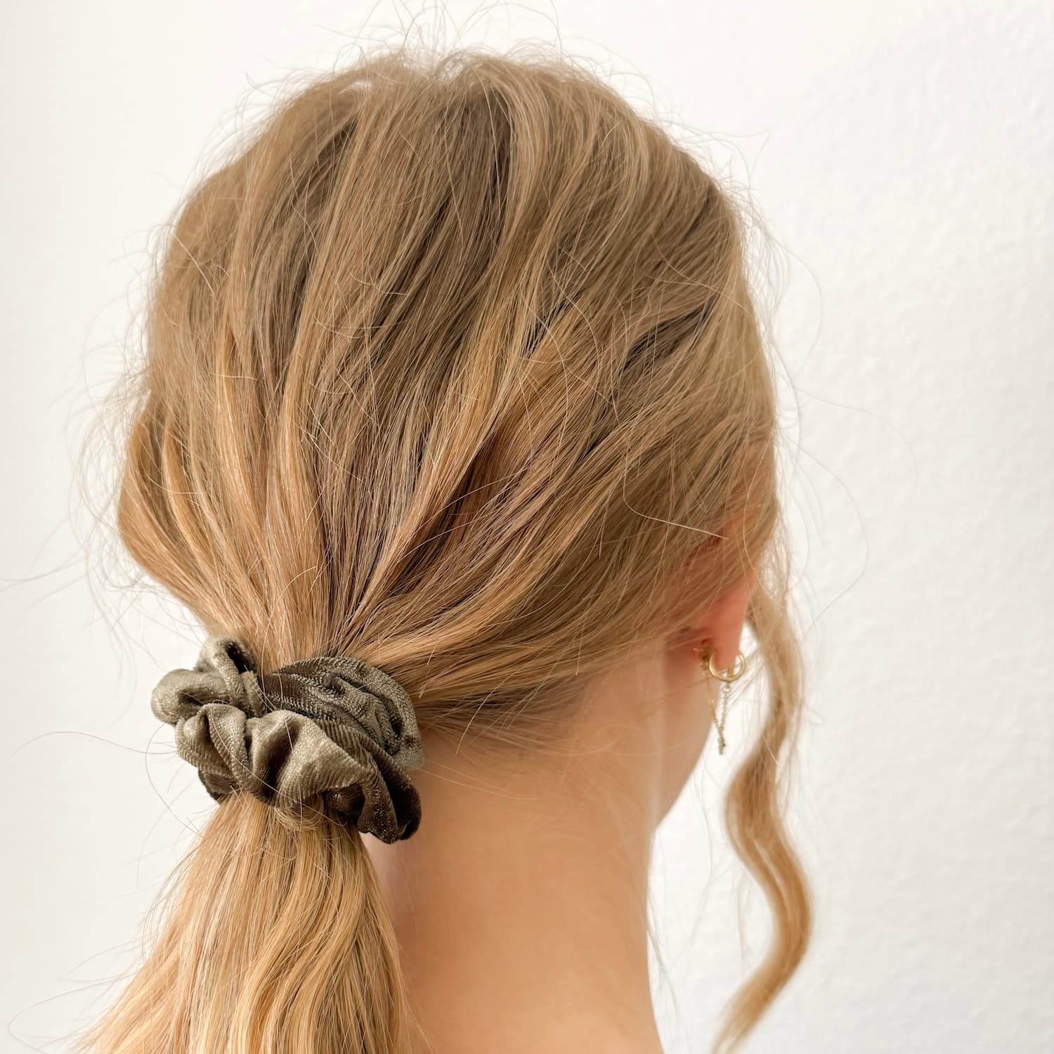 Auf dem Bild ist ein dunkelgrünes Scrunchie zu sehen, das Scrunchie wird getragen präsentiert.