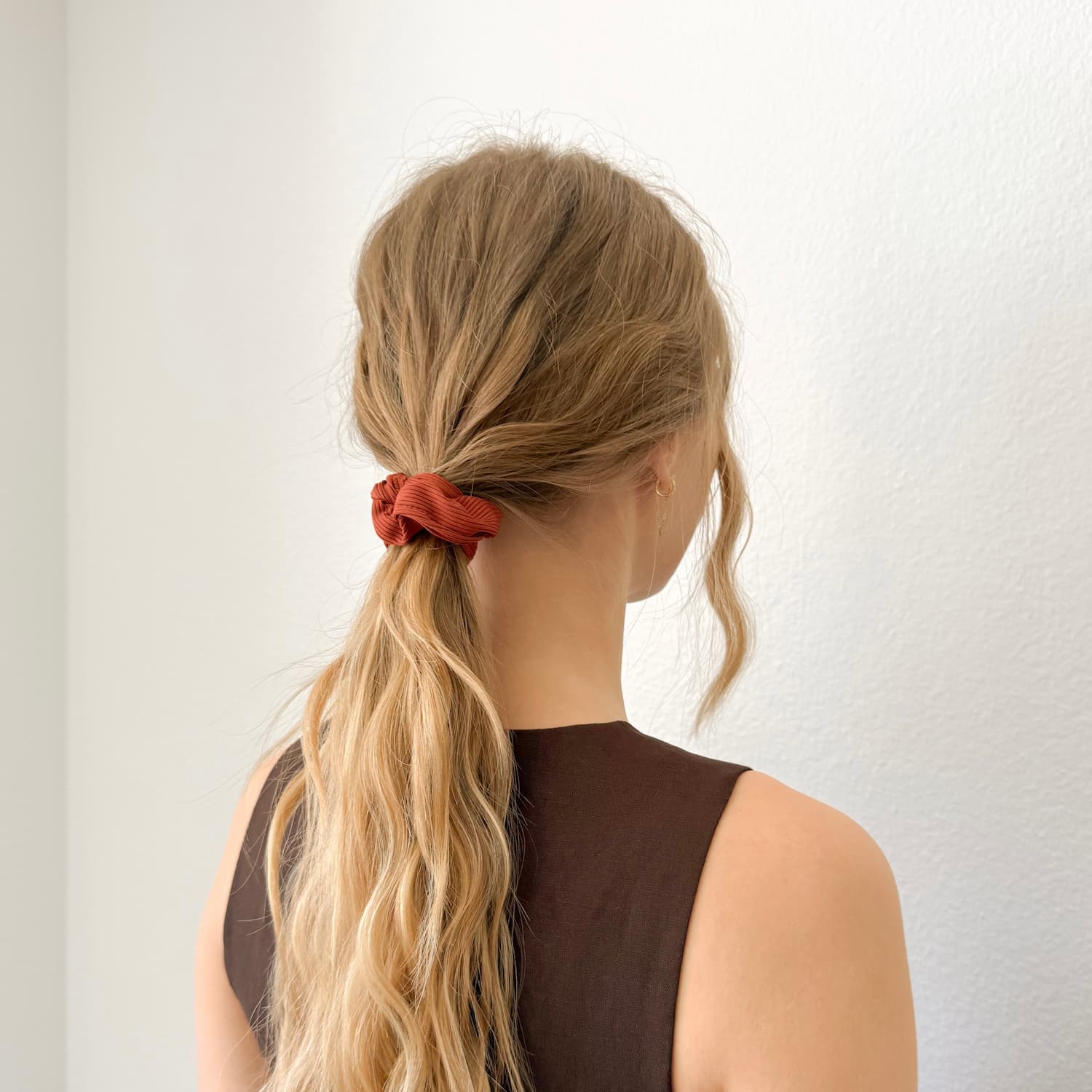Auf dem Bild ist ein gerilltes Scrunchies in rot zu sehen, das Scrunchie wird getragen präsentiert.