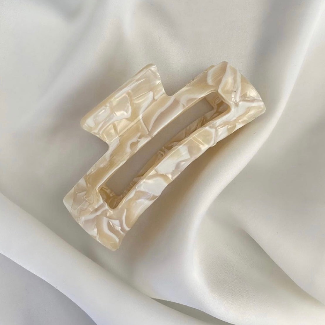 Eine beige mittelgrosse Haarspange (7cm) auf einem weissen samtigen Tuch