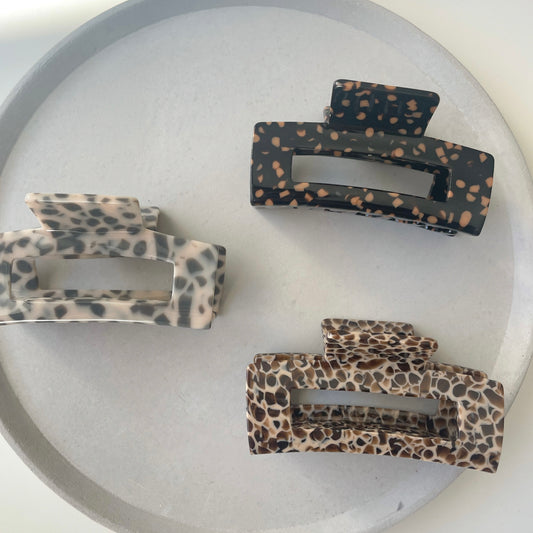 drei mittelgrosse Haarklammern mit ausgefallenem Muster auf einem grauen Schmucktablett