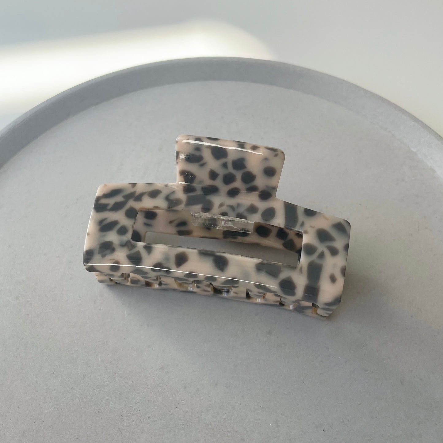 eine mittelgrosse längliche Haarspange in grau mit einem Muster welches an einen bubble tea erinnert